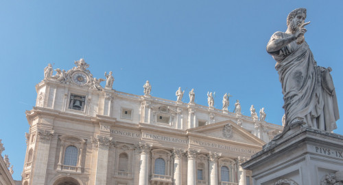 Posąg św. Piotra na tle fasady bazyliki San Pietro in Vaticano